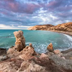 Petra tou Romiou (Skała Afrodyty) na Cyprze o zachodzie słońca, z turkusowym morzem i skalistym wybrzeżem.