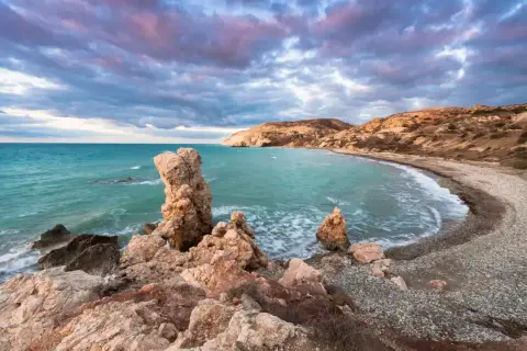 Petra tou Romiou (Skała Afrodyty) na Cyprze o zachodzie słońca, z turkusowym morzem i skalistym wybrzeżem.