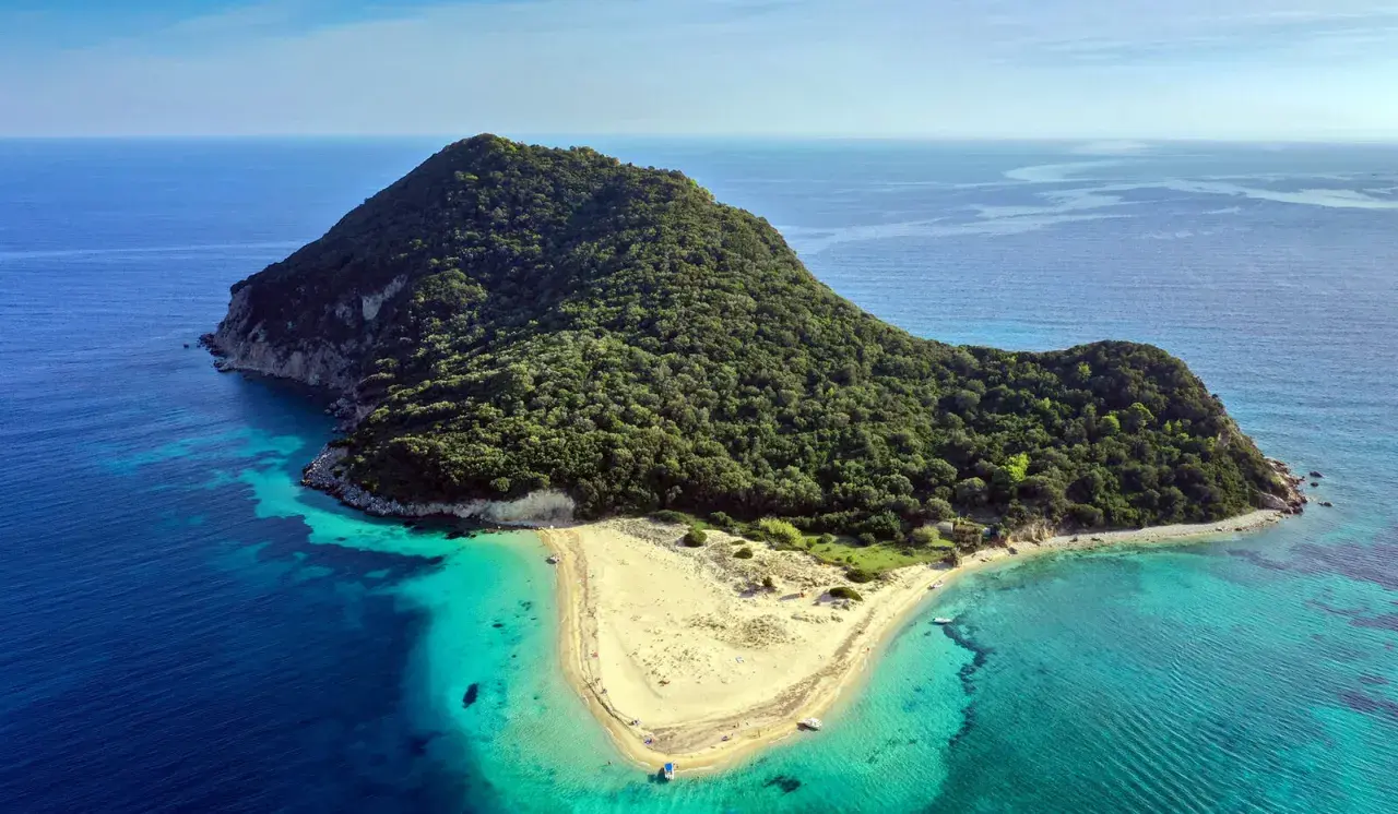 Malownicza wyspa żółwi Zakynthos, porośnięta zielenią, z piaszczystą plażą i krystalicznie czystą wodą.