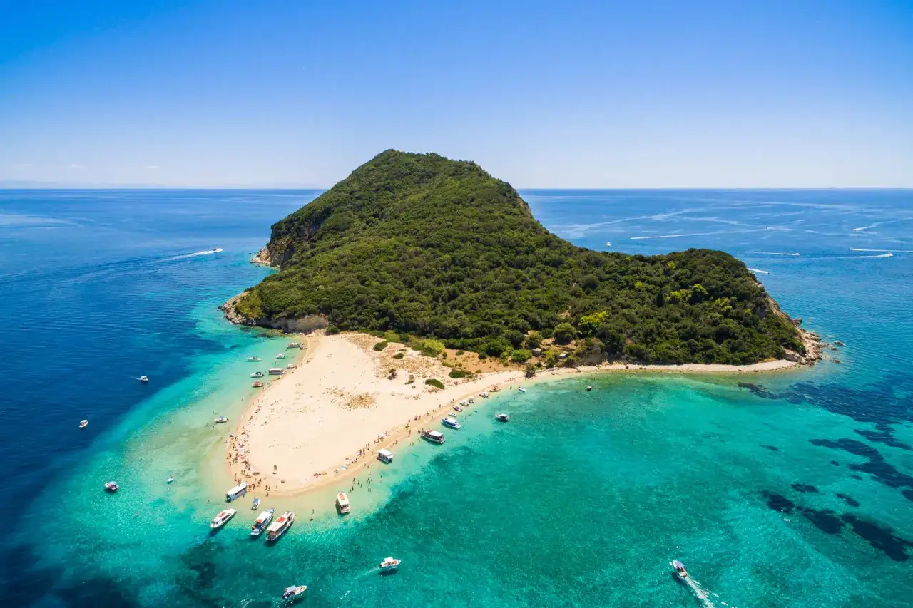 Malownicza wyspa żółwi na Zakynthos, z piaszczystą plażą, turkusową wodą i łodziami.